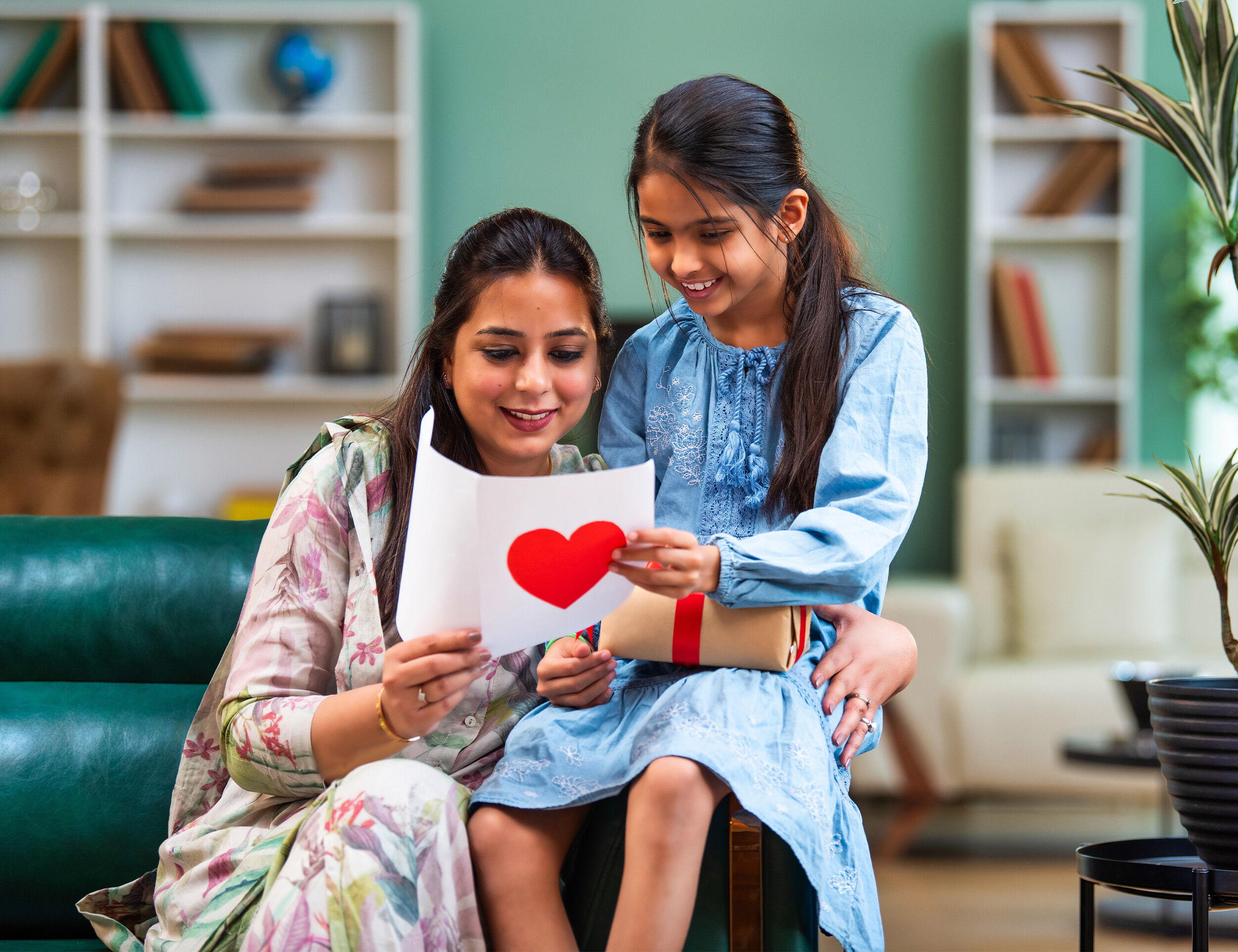 Daughter showing hand made mothers day card to her mother on mother day